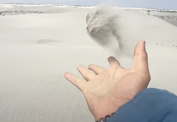 „A cool slow-mo shot in the desert of the sand blowing in the wind“